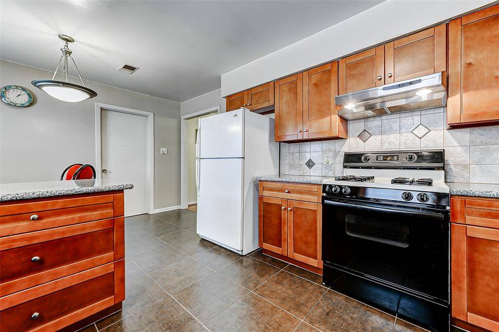 Charming kitchen space featuring ample cabinetry, a large breakfast nook, and neutral tile floors for easy maintenance. Fresh lighting fixtures and a clean design offer functionality and flexibility for everyday living.