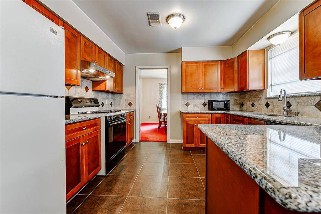 This kitchen blends functionality and style with gorgeous granite countertops, detailed backsplash work, and an abundance of storage. The layout offers plenty of room for meal prep, while the natural flow into the dining area is perfect for gatherings.
