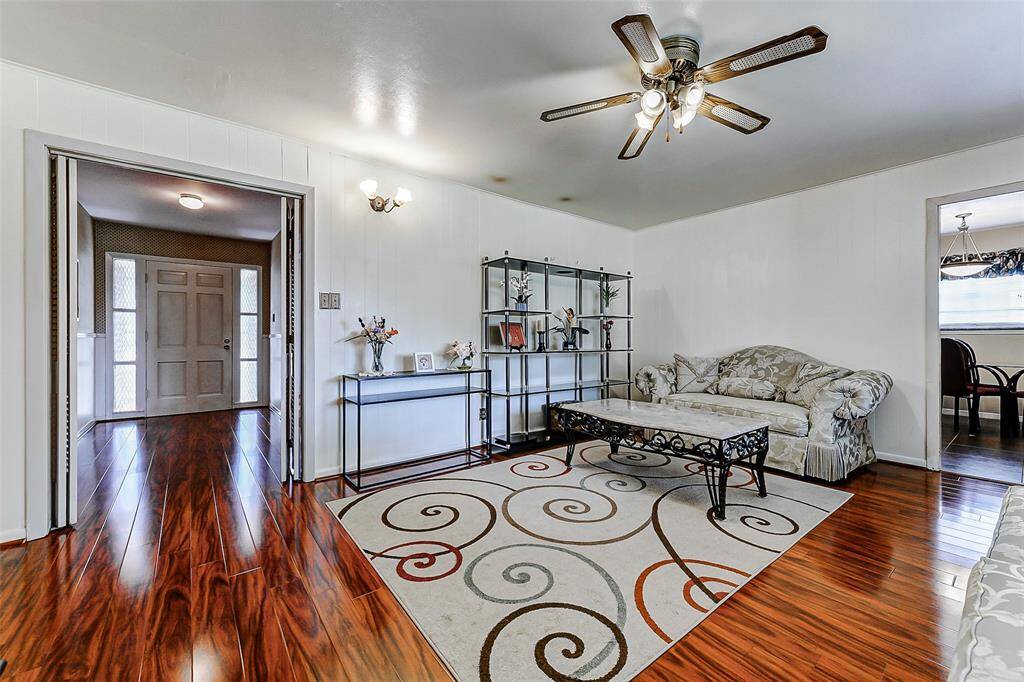 Beautifully maintained living room showcasing gleaming wood floors, decorative lighting, and a neutral palette ready for your design ideas. The open sightlines to the entryway and kitchen make this an entertainer’s dream.