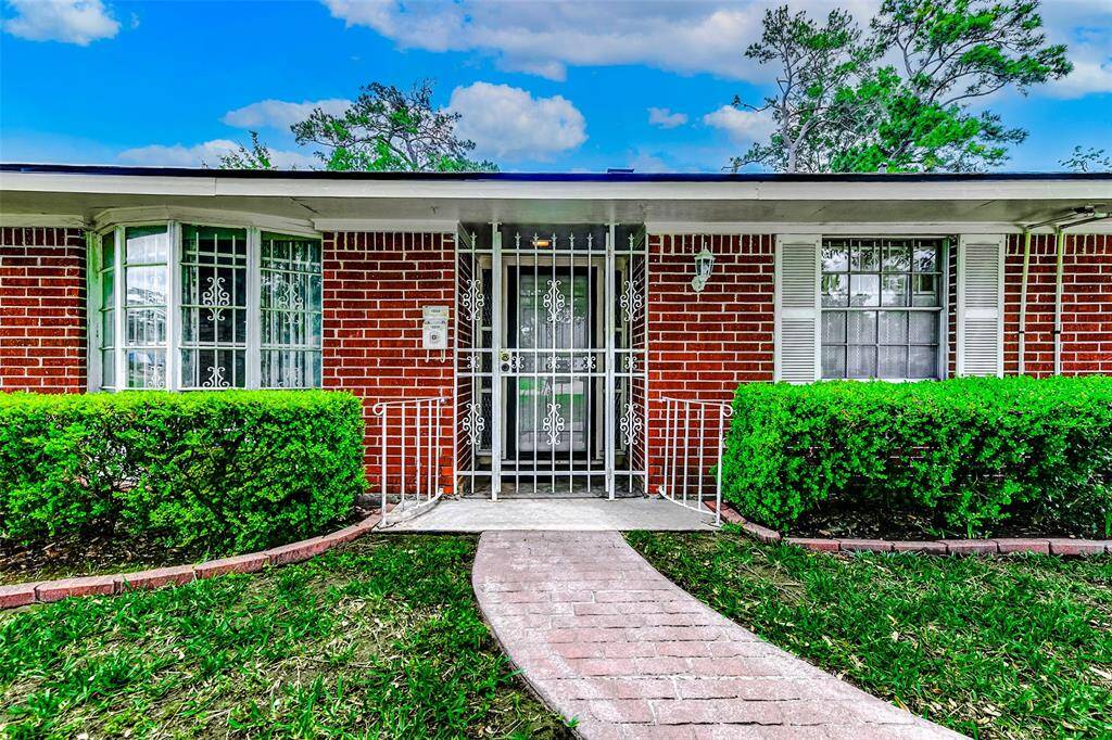 The welcoming entry is framed by classic wrought iron accents and brick pathways that create a nostalgic and secure sense of home. Fresh greenery and thoughtful landscaping enhance the inviting first steps inside this lovingly maintained property.