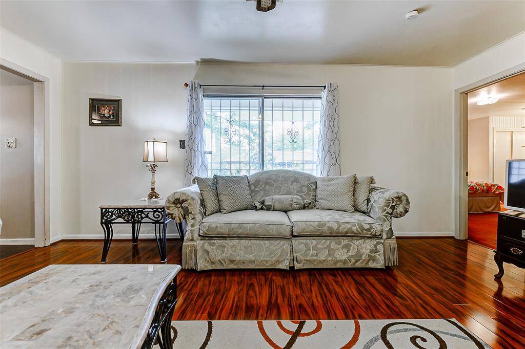 Sun-drenched living area with large front-facing windows and custom security bars. Crisp white walls and classic trim offer a neutral palette ready for your personal touch. Cozy, comfortable, and full of natural light.