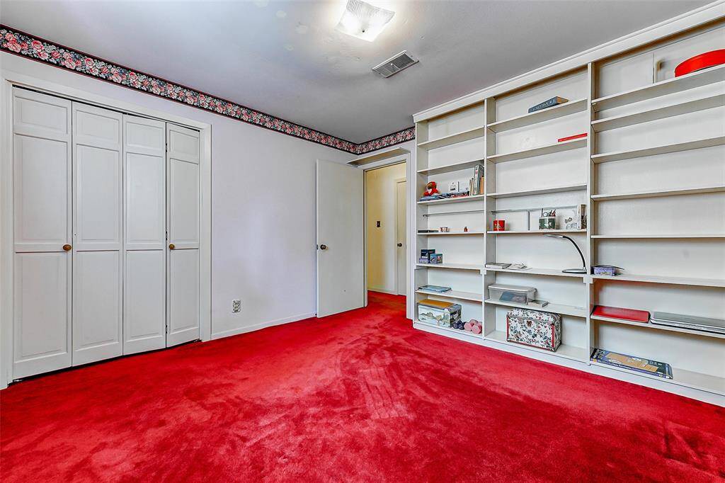 Flexible space featuring built-in shelving, closet storage, and bold carpeting. Ideal for a home office, study room, or extra bedroom with plenty of space to organize books, art, or collectibles.