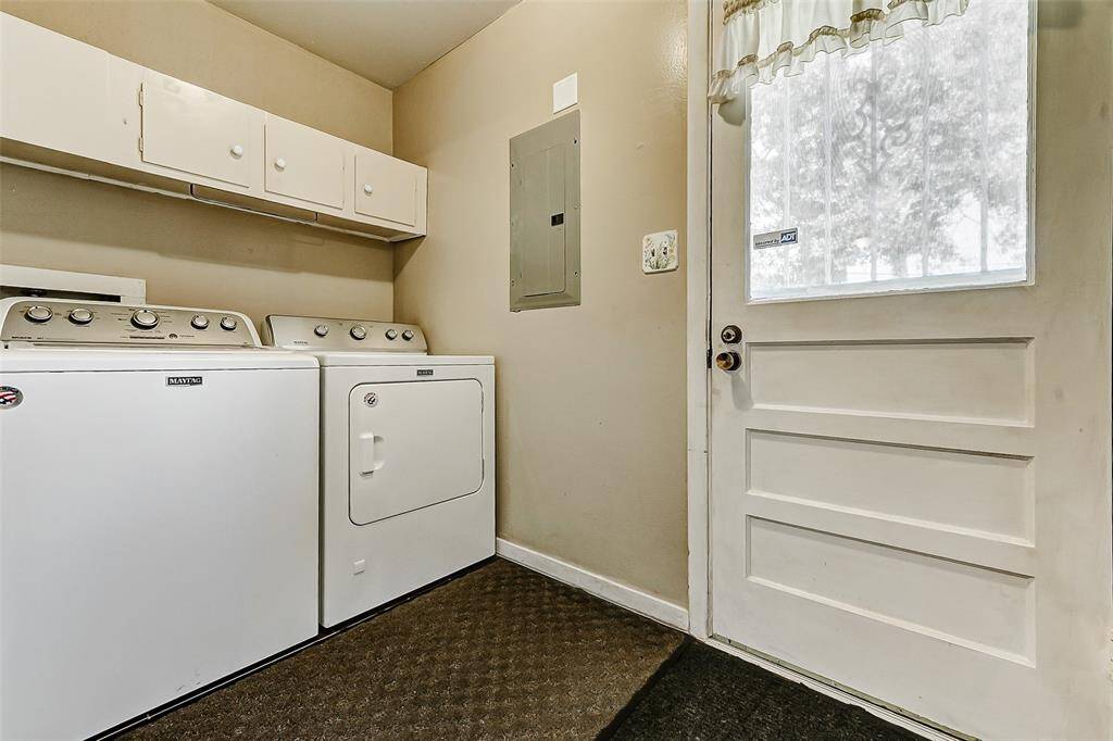 Convenient and functional, this laundry room features overhead storage cabinets, and easy access to the backyard through a bright glass-paneled door. Perfect for everyday living and organization.