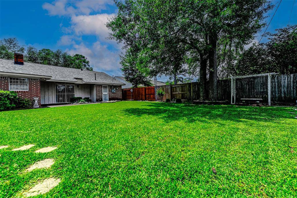 Stunning backyard setting with a wide open grassy area, shady trees, and privacy fencing. This outdoor space offers the perfect backdrop for playtime, parties, and everyday relaxation.