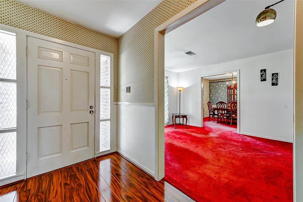 Natural light floods the entry and living areas, highlighting period details like rich red carpet and original architectural charm. A flexible floorplan offers the perfect canvas to personalize and update while maintaining the classic vibe.