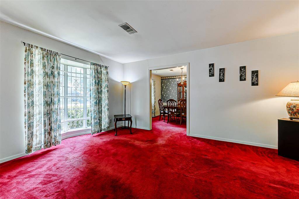 Spacious living room with a large bay window overlooking the front yard and a seamless flow into the formal dining room. Imagine gathering with loved ones or hosting cozy dinners in a space that’s ready for a fresh vision and easy updates.