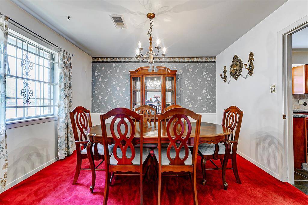 Elegant formal dining room with classic wallpaper and ornate light fixture, offering a sophisticated setting for hosting family dinners or festive gatherings.