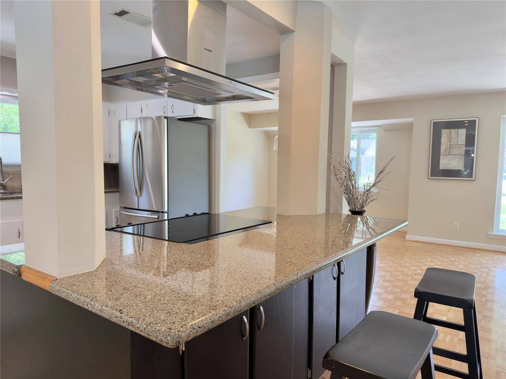Kitchen island seating to chat with the chef. Note the glass cooktop and island venting