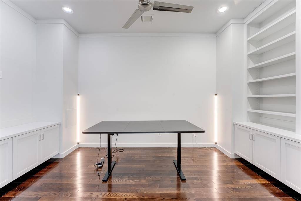 Built-in white cabinetry with ample storage, and modern recessed lighting while open shelving provides display space.