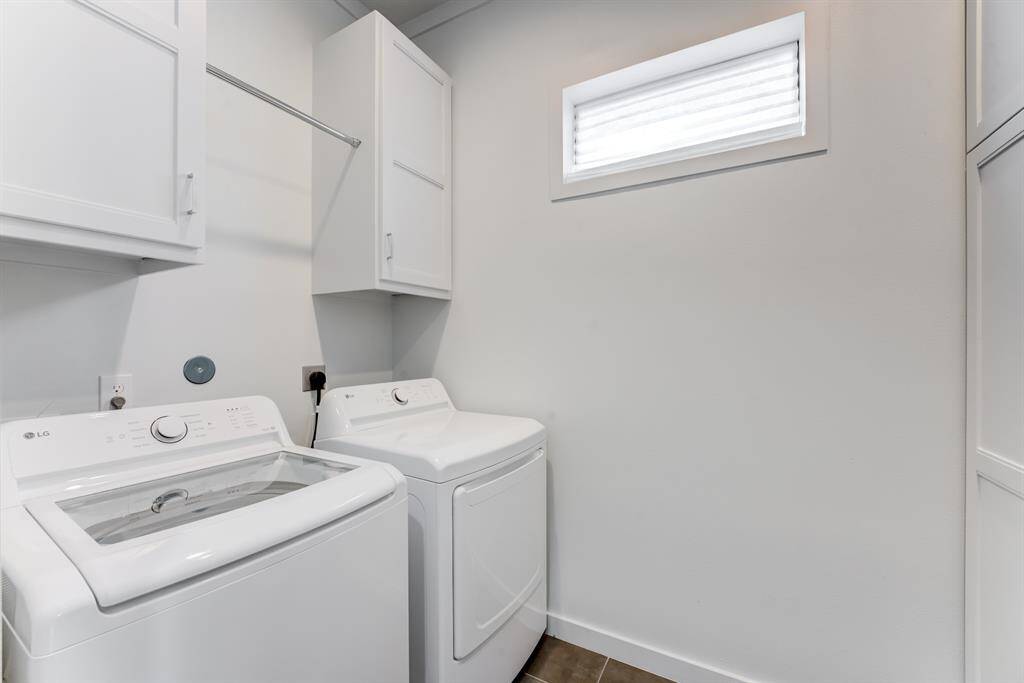 This laundry room features modern appliances, ample cabinetry for storage, and a small window for natural light.