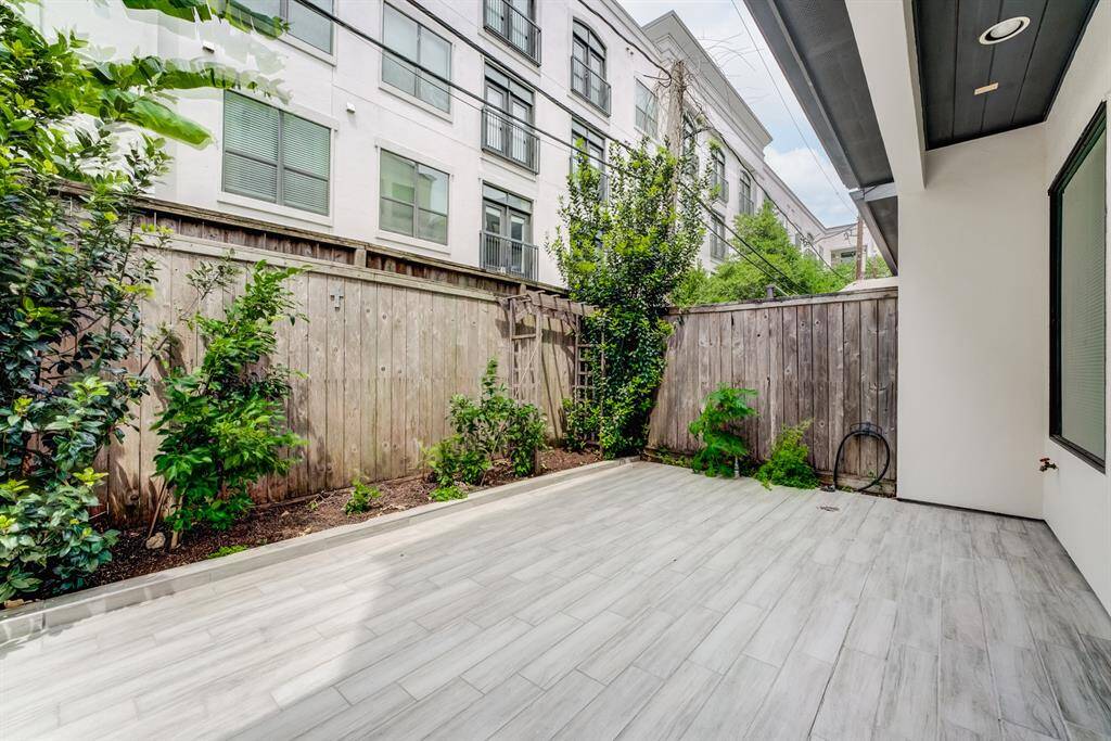 This photo showcases a private, fenced backyard featuring a clean, tiled patio with some greenery along the edges. It's ideal for low-maintenance outdoor living and entertaining.