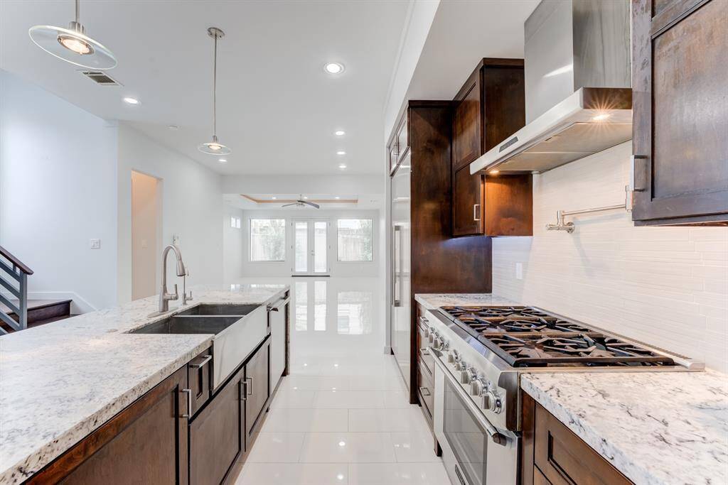 Bright, open layout with a large island and pendant lighting, leading to a spacious living area with natural light from large windows.