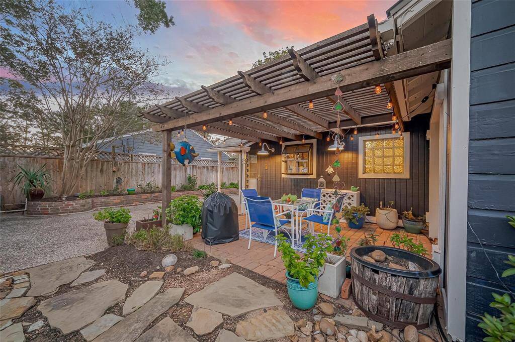 View of the pergola from the fire pit. You can see the backdoor to the kitchen on your left.  The French doors to the primary are flush with the wall on the right.