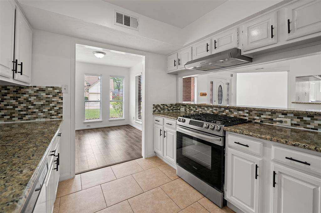 Kitchen has granite countertops with custom tile backsplash.