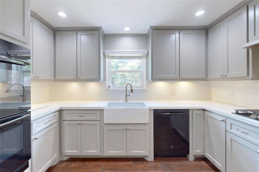The kitchen has been updated with a farmers sink, all new custom cabinets, quartz countertops, double ovens, and tile backsplash.
