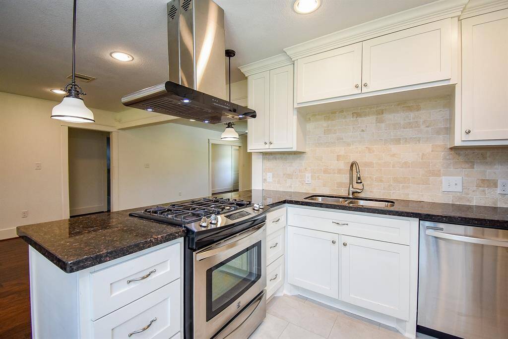 Spacious kitchen featuring granite countertops and a stylish tile backsplash.
