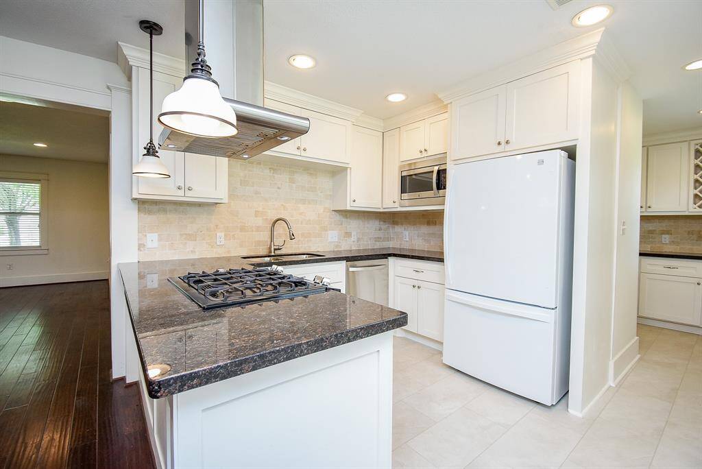 Spacious kitchen featuring granite countertops and a stylish tile backsplash.