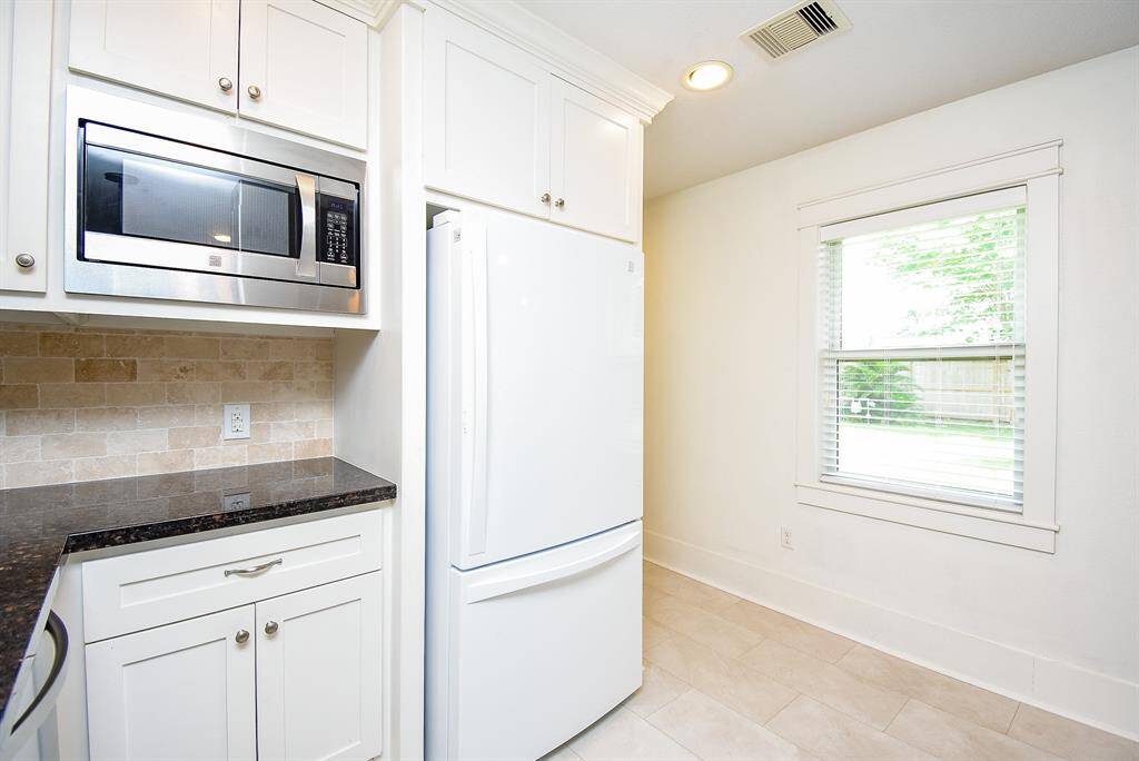 Spacious kitchen featuring granite countertops and a stylish tile backsplash.