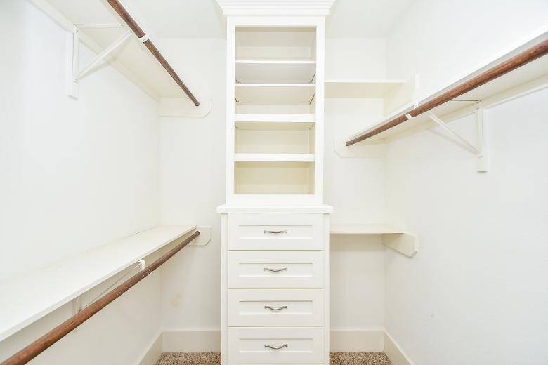Master walk-in closet includes built-in drawers and shelves for convenient storage.
