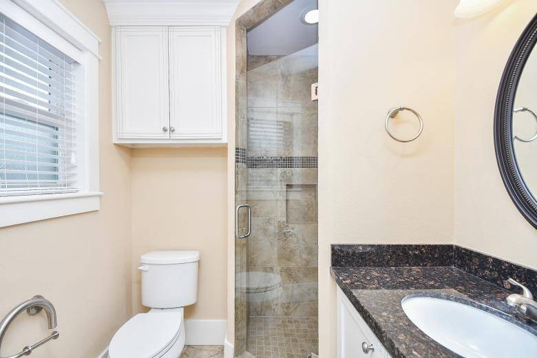 Updated master bathroom featuring a walk-in shower and granite-topped vanity.