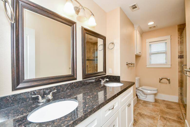 Generously sized secondary bathroom boasting a dual sink vanity with granite tops and a walk-in shower with stylish tile surround.