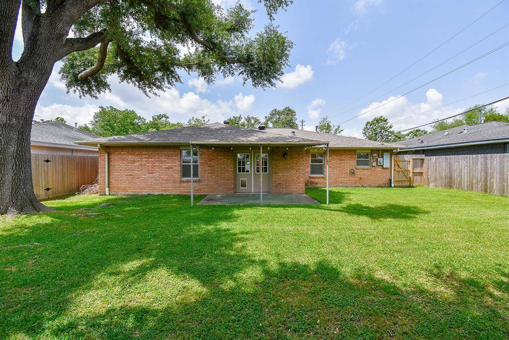 Beautifully landscaped backyard with a sprawling lawn and a mature tree offering shade and privacy.