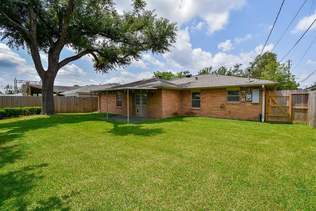 Beautifully landscaped backyard with a sprawling lawn and a mature tree offering shade and privacy.