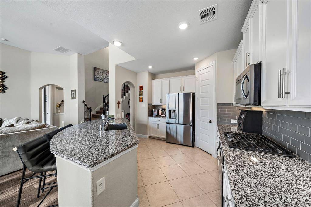 Sleek stainless steel appliances, a five-burner gas cooktop, and ample counter space make this kitchen a true chef’s delight. The generous storage and large pantry provide plenty of functionality to match the home's elegant design.