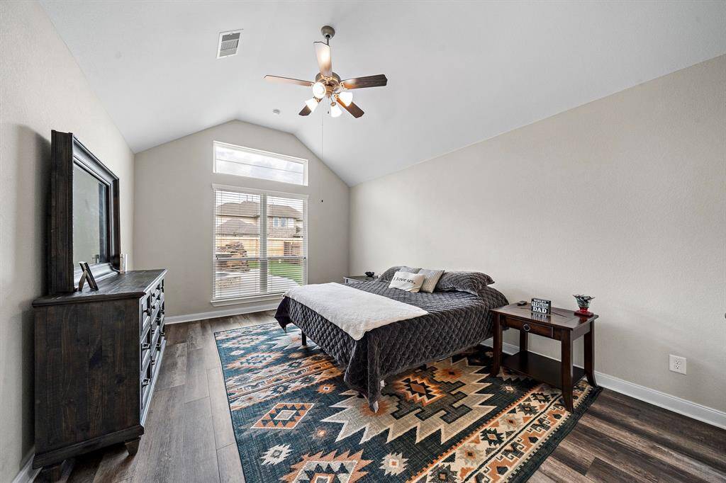 The spacious primary suite is a true retreat, featuring vaulted ceilings and expansive windows that fill the room with natural light. Enjoy peaceful views of the backyard and pool right from the comfort of your bedroom.