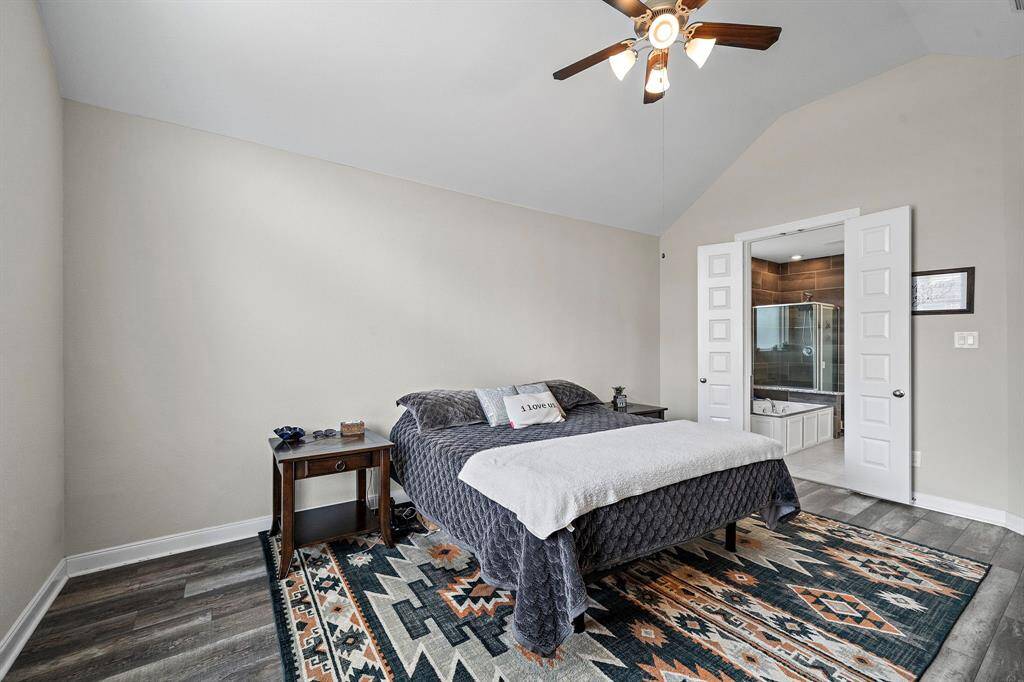 This serene primary bedroom offers direct access to a spa-inspired bathroom, combining comfort and convenience. Neutral tones and luxury vinyl plank flooring create a calm, inviting atmosphere.