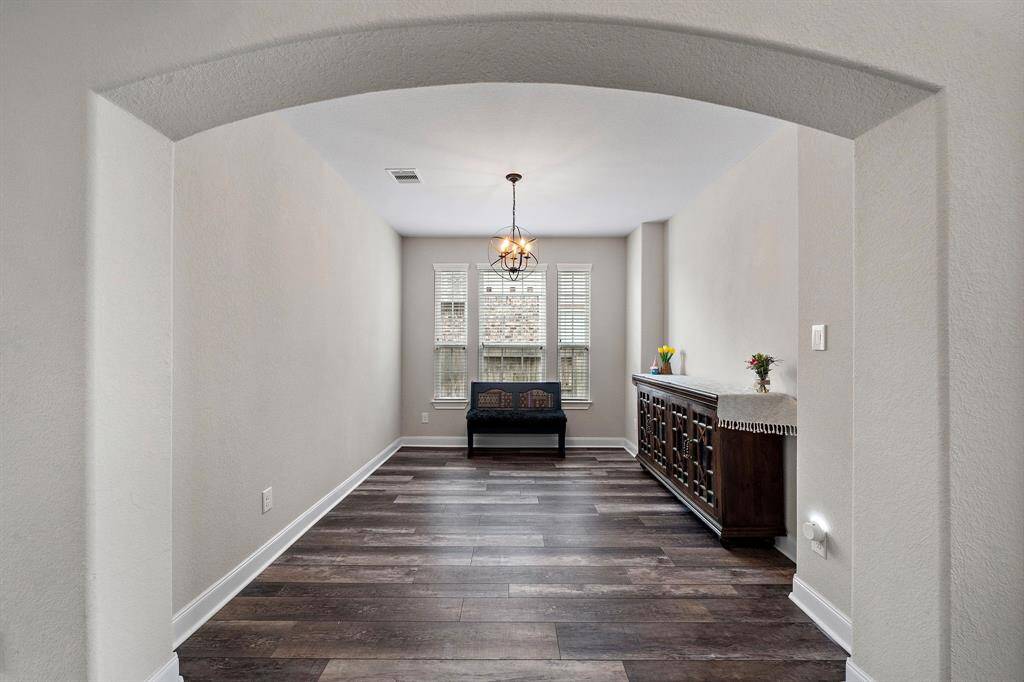 The formal dining room offers an elegant space framed by an arched entryway and filled with natural light from a trio of tall windows. Its versatile layout and updated flooring make it ideal for holiday gatherings or intimate dinners.