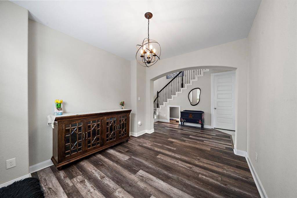 This beautifully connected dining area sits just off the main hallway, providing a seamless flow to the kitchen and living spaces. Architectural touches like the archway and iron spindle staircase nearby add to the home's sophisticated charm.