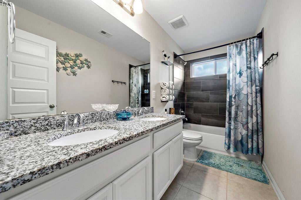 The upstairs full bath is beautifully updated with granite counters, dual sinks, and modern fixtures. A stylish tiled tub and shower combination make it both practical and polished for everyday living.