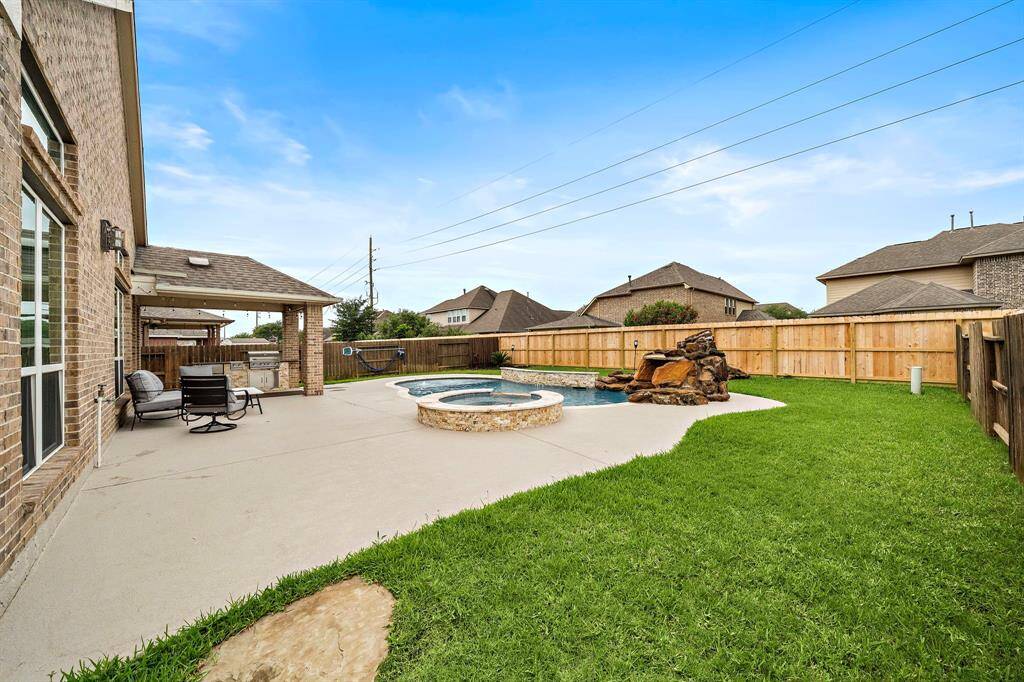 Enjoy effortless outdoor living with this resort-style backyard, featuring a custom-built pool with spa and upgraded stone accents. A lush lawn frames the patio and pool area, offering plenty of space to play or host gatherings.