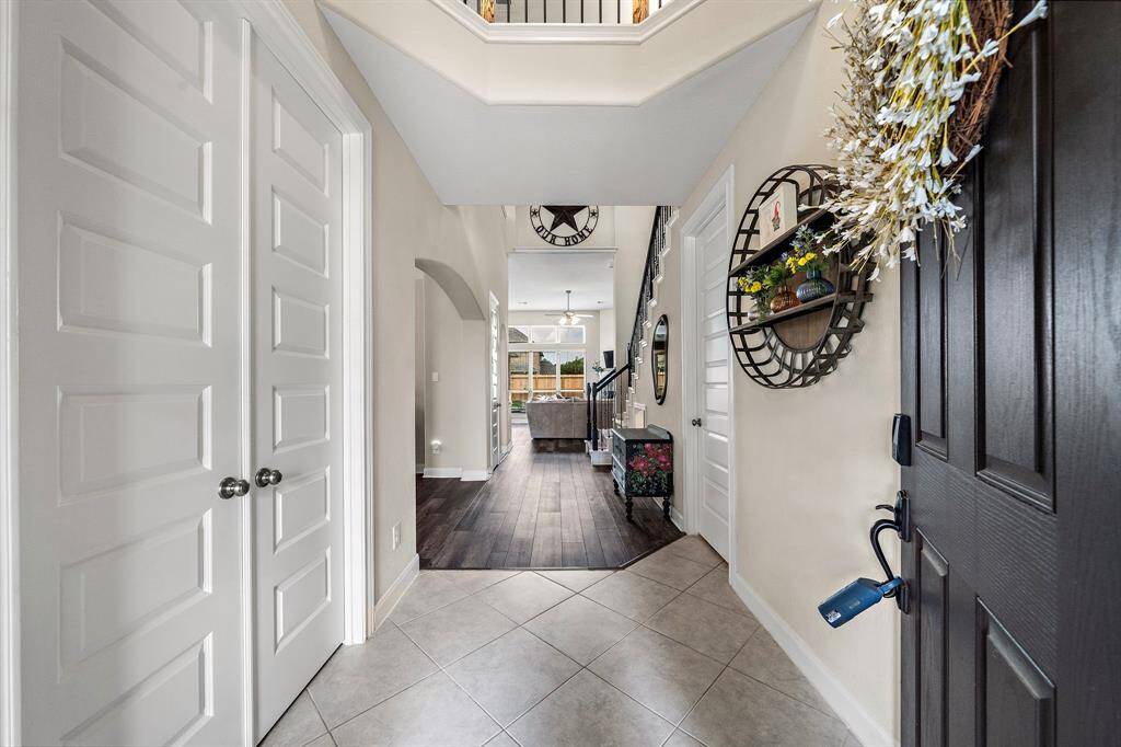 Step inside to a welcoming foyer accented by soaring ceilings, elegant iron staircase railings, and a view straight through to the open-concept living spaces. The bright and airy entry sets the tone for the thoughtfully designed interior.
