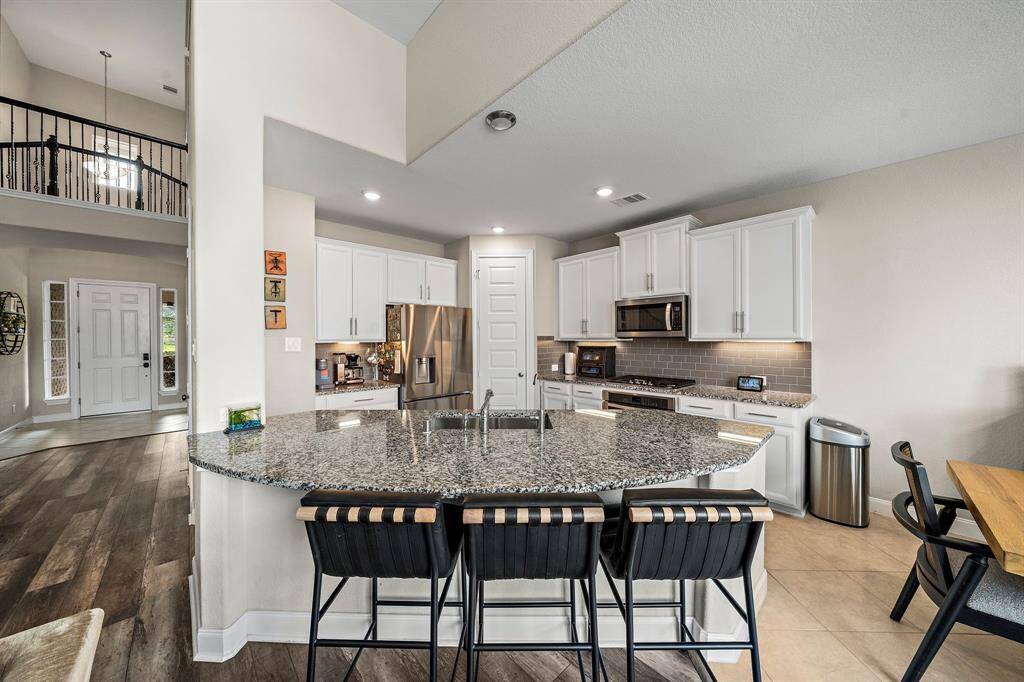A large granite island with bar seating creates the perfect spot for casual dining, morning coffee, or evening gatherings. The open layout keeps the kitchen at the heart of the home, providing easy access to the main entry and living areas.