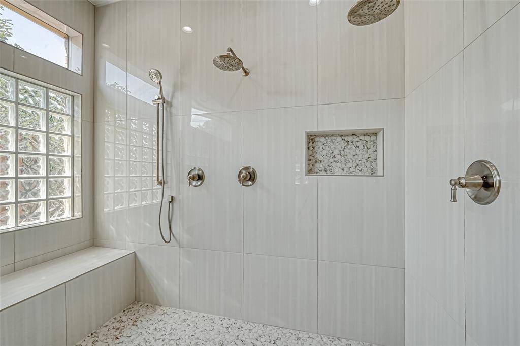 CHECK OUT THE CLOSE-UP VIEW OF THE SHOWER WITH BUILT-IN BENCH AND MULTIPLE SHOWER HEADS.