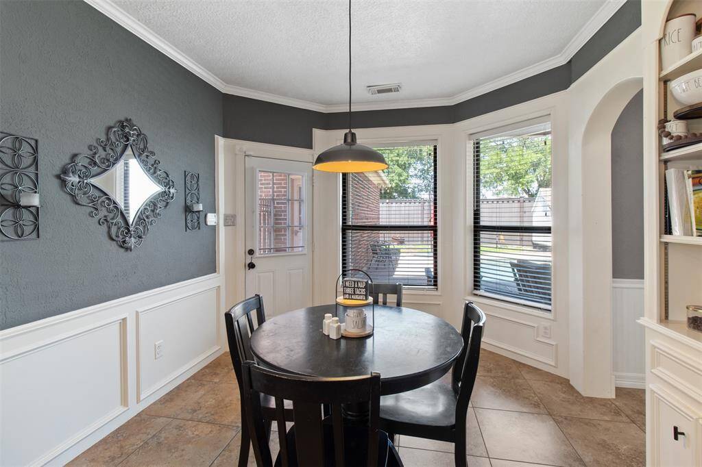 This elegant breakfast nook features  charming chair rail molding and windows with a view of the pool.