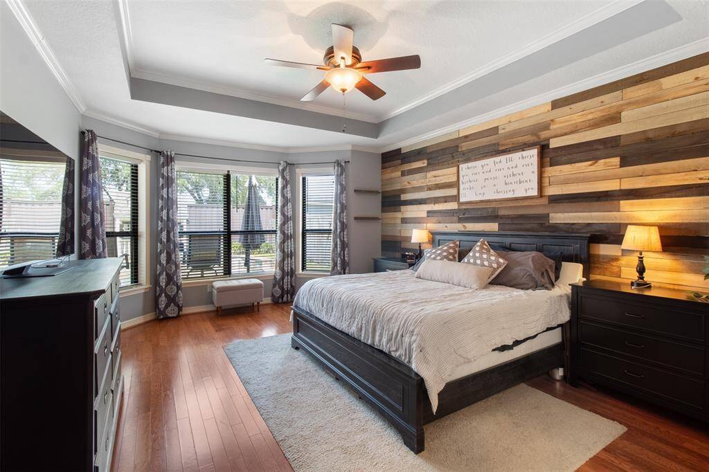Experience tranquility in the primary retreat featuring beautiful wood floors, expansive windows, and tall ceilings.