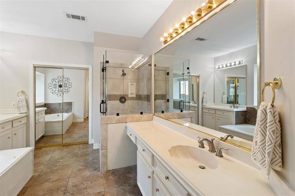 Experience luxury in the primary bathroom with dual vanities, a separate tub, and a walk-in shower.