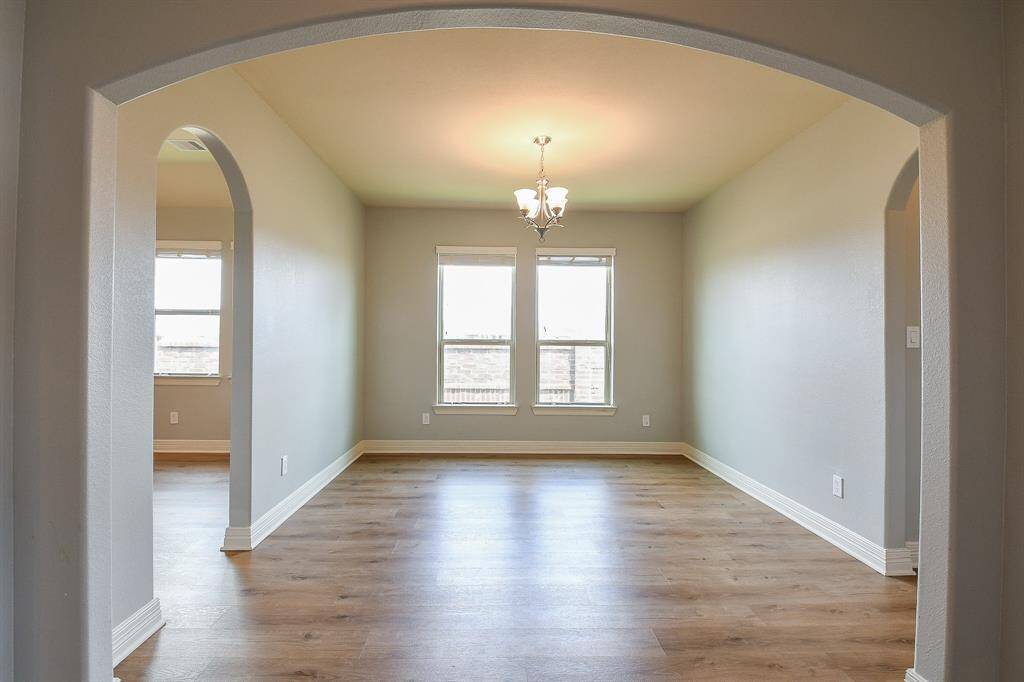 Two large windows offer natural light, and arched doorways add an elegant touch.