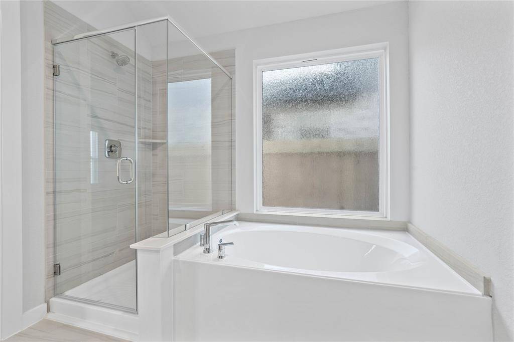 Additional view of the primary bathroom features a dark framed walk-in shower with tile surround, separate garden tub for soaking after a long day with custom tile detailing, high ceilings, custom paint, sleek and dark modern finishes!