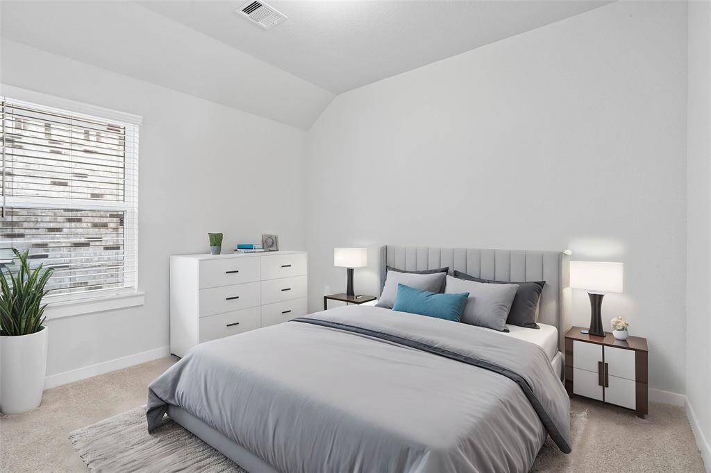 Secondary bedroom features plush carpet, custom paint, lighting, and a large window with privacy blinds.