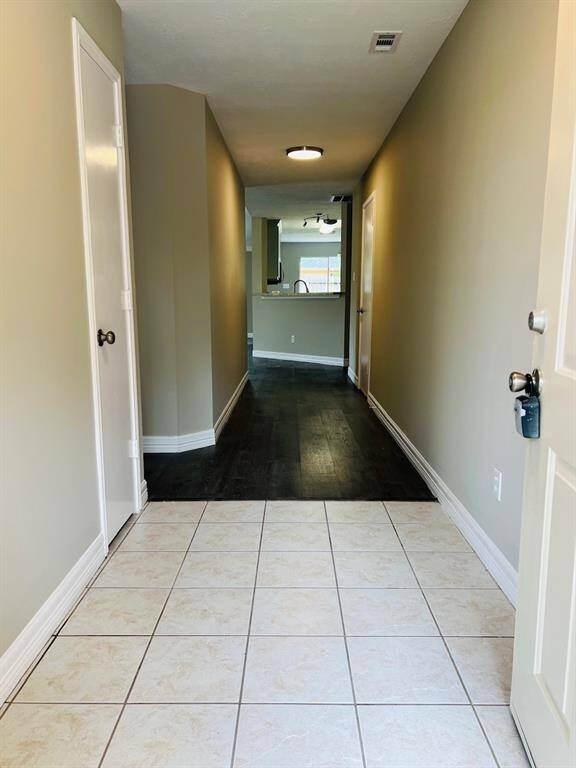 The space leads to an open area with a kitchen visible in the background.