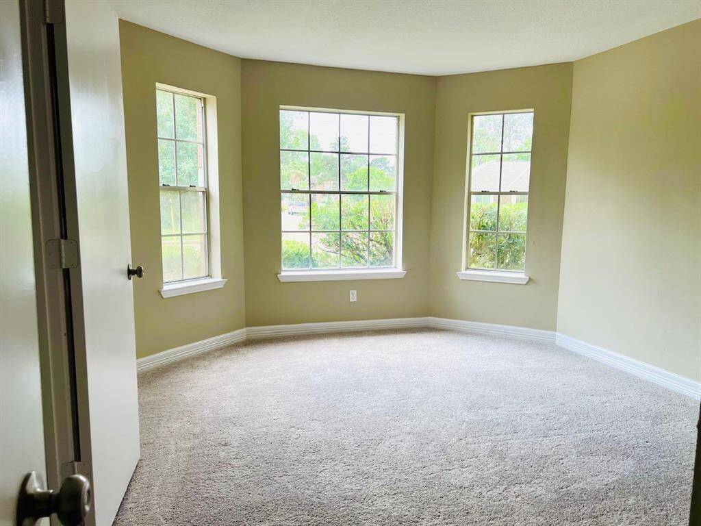Bedroom 2 features a cozy carpeted floor with a bay window area, offering plenty of natural light and a pleasant view of the greenery outside. The neutral walls provide a versatile backdrop for any decor style.