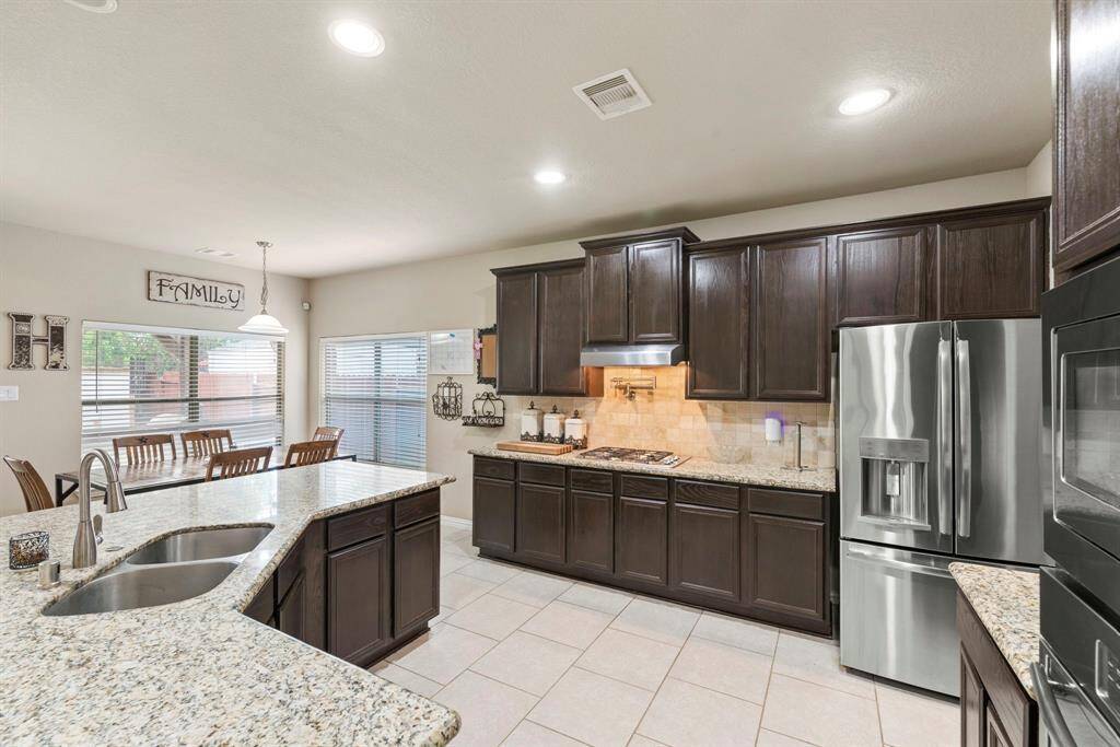This kitchen features dark wood cabinetry, granite countertops, and stainless steel appliances!
