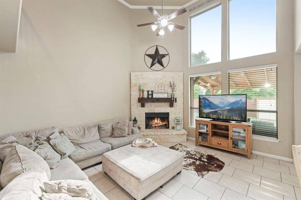 This inviting living room features high ceilings, large windows for abundant natural light plus a cozy stone fireplace!