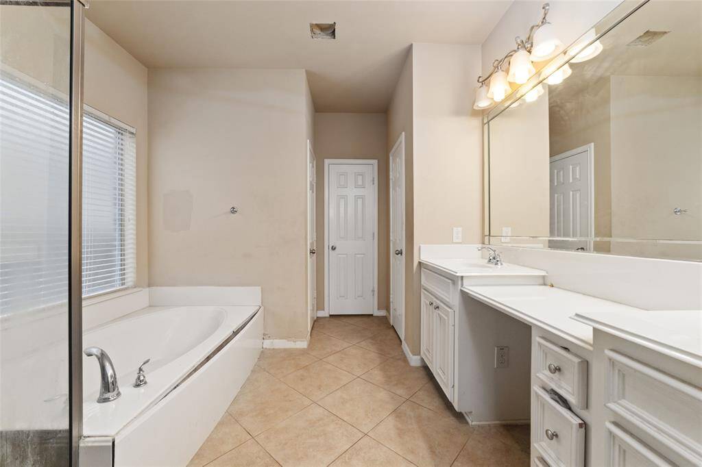 Primary bathroom with double vanity, bath tub and shower.