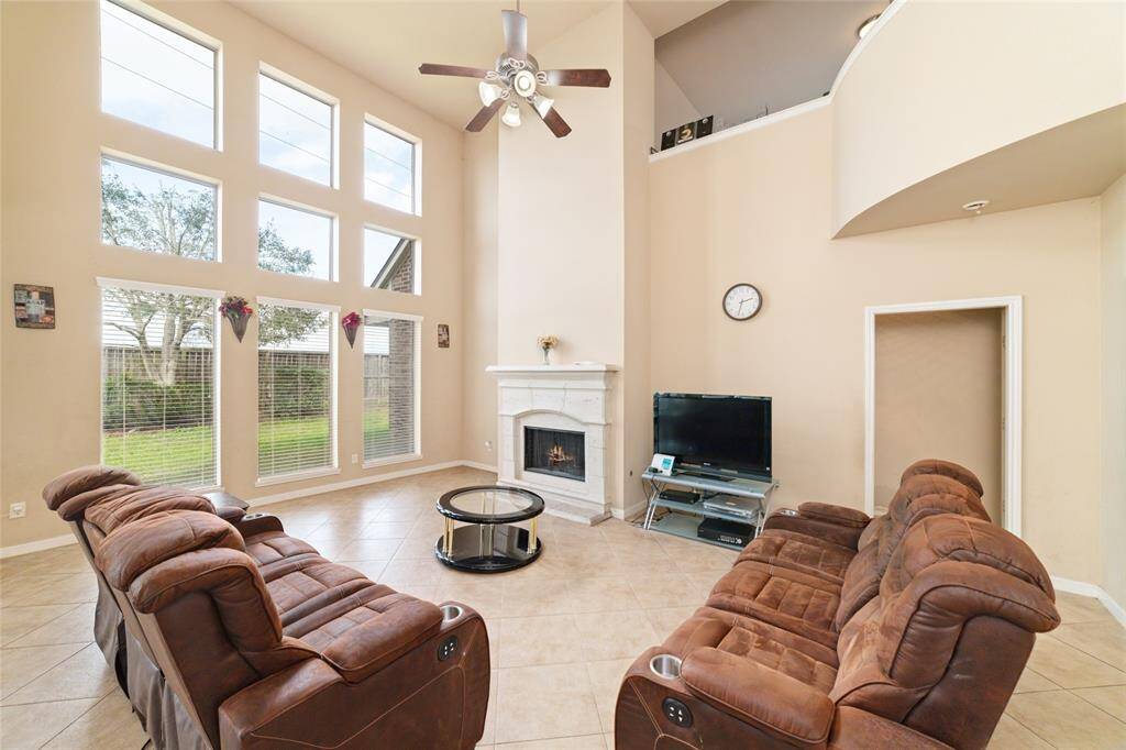 Spacious family room features high-ceiling with a wall of window makes it so airy and bright.