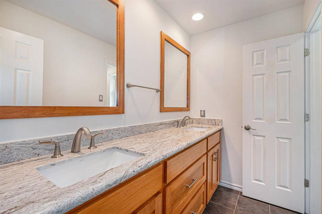 Secondary bathroom offers dual sinks and a combination tub and shower.